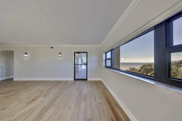 a view of an empty room with a window and wooden floor