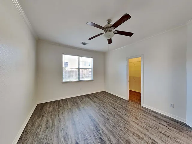 a view of empty room with wooden floor and fan