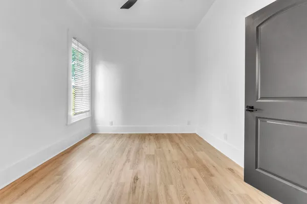 a view of an empty room with wooden floor and a window