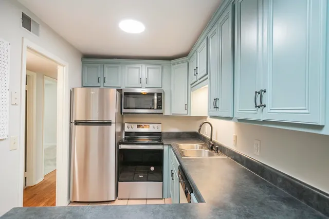 a kitchen with granite countertop a refrigerator and a sink