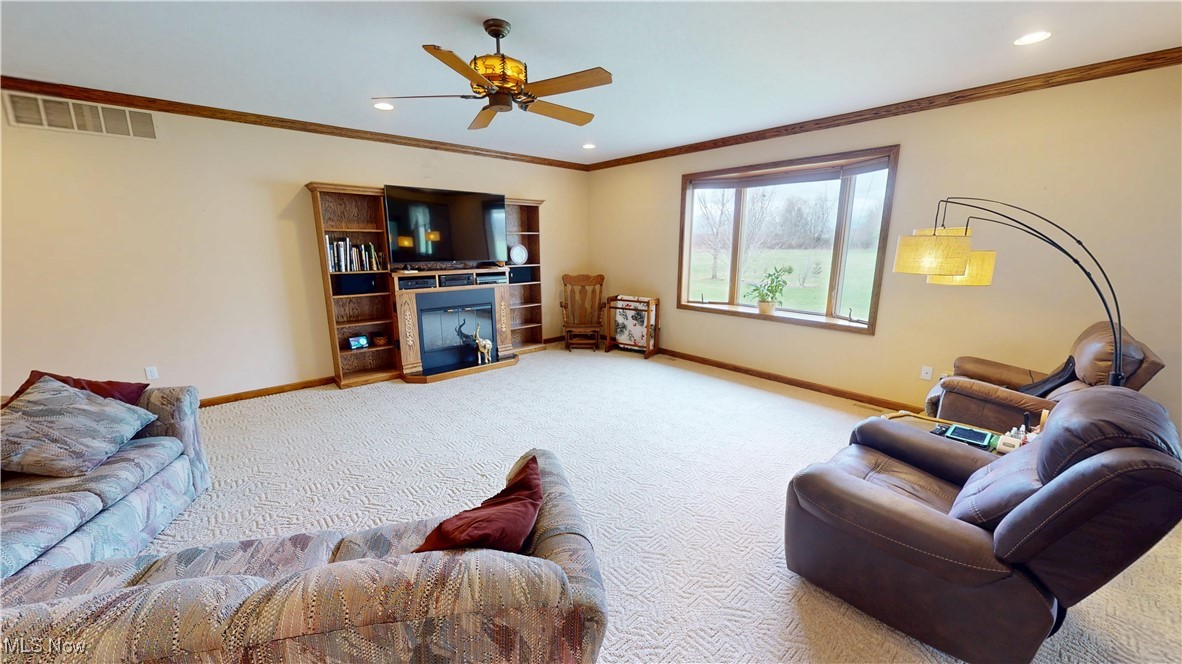 10323 Smith Road Litchfield, OH 44253 - Photo 9 of 50 Carpeted living area with a ceiling fan, baseboards, visible vents, ornamental molding, and recessed lighting