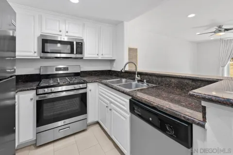 a kitchen with granite countertop a stove sink and microwave