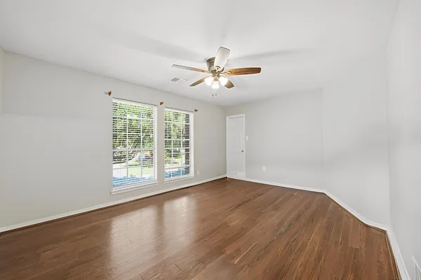 an empty room with wooden floor and windows