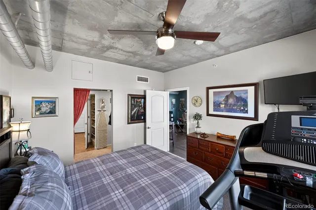 a bedroom with a bed and dresser with wooden floor