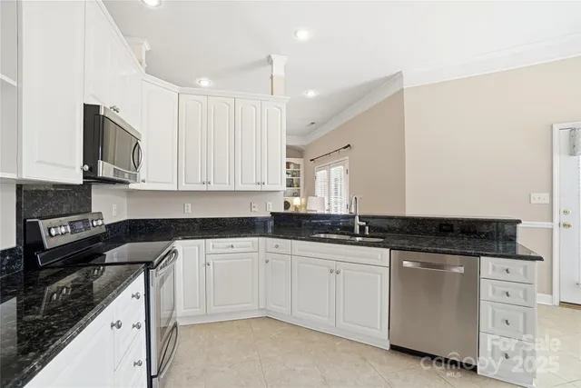 a kitchen with granite countertop white cabinets white stainless steel appliances with a sink and dishwasher
