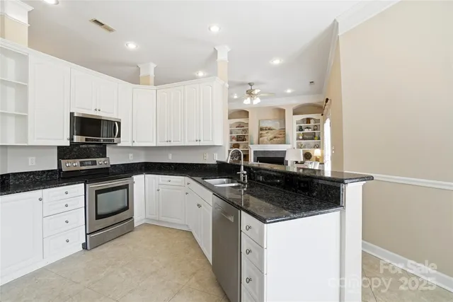 a kitchen with granite countertop a sink and white cabinets