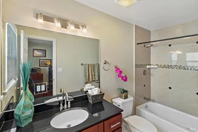 a bathroom with a granite countertop sink mirror vanity and toilet