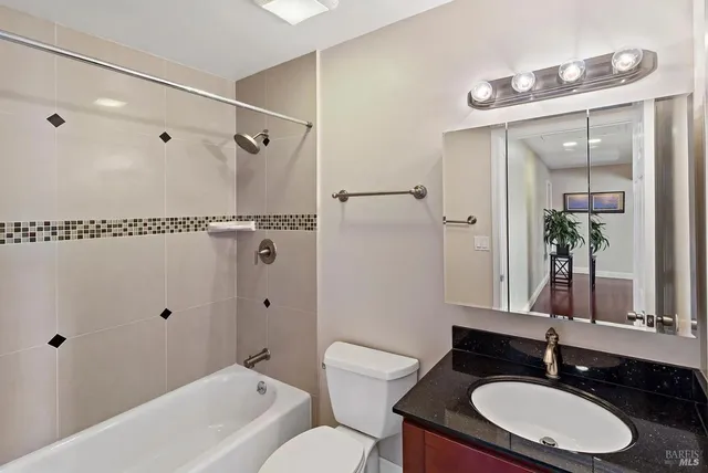 a bathroom with a granite countertop sink toilet a large mirror a shower and a bathtub