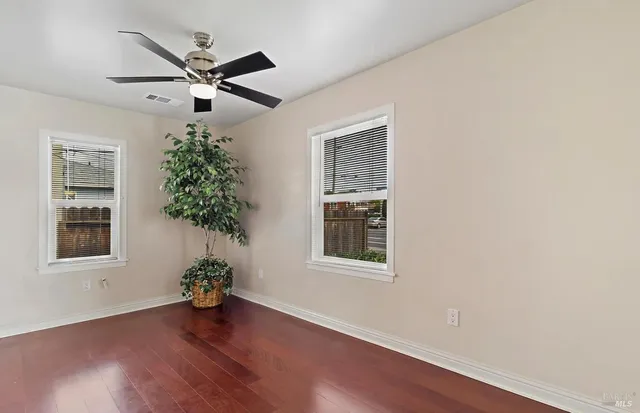 an empty room with wooden floor a potted plant and a window