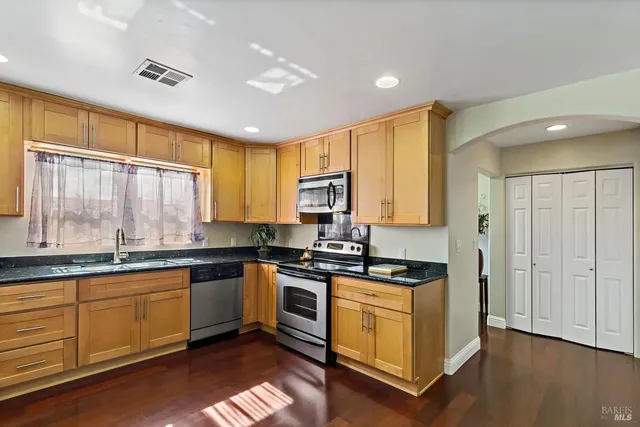 a kitchen with stainless steel appliances granite countertop a stove a sink and a microwave