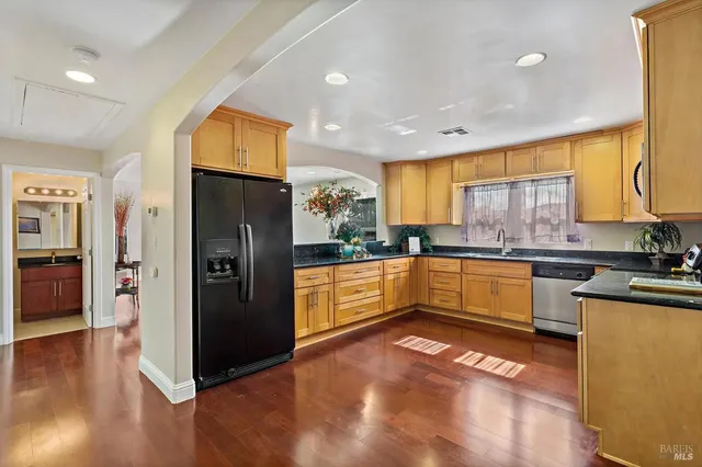 a large kitchen with stainless steel appliances granite countertop a refrigerator a sink dishwasher a stove and white countertops with wooden floor