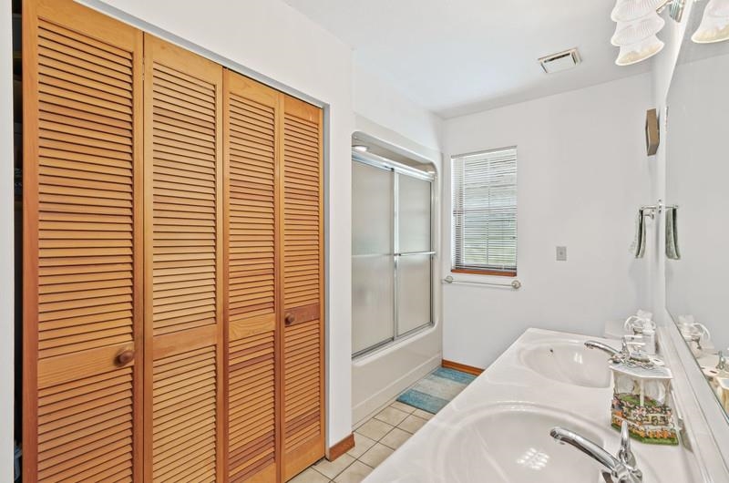 2650 Cabbage Hammock Road St. Augustine, FL 32092 - Photo 23 of 91 Bathroom featuring a closet, tile patterned floors, double vanity, and shower / bath combination with glass door