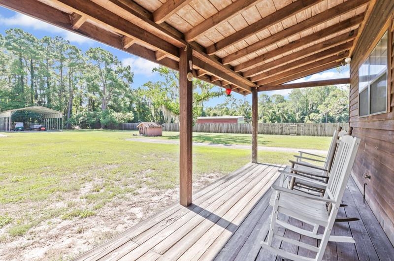2650 Cabbage Hammock Road St. Augustine, FL 32092 - Photo 45 of 91 Deck with a detached carport, view of scattered trees, and a fenced backyard