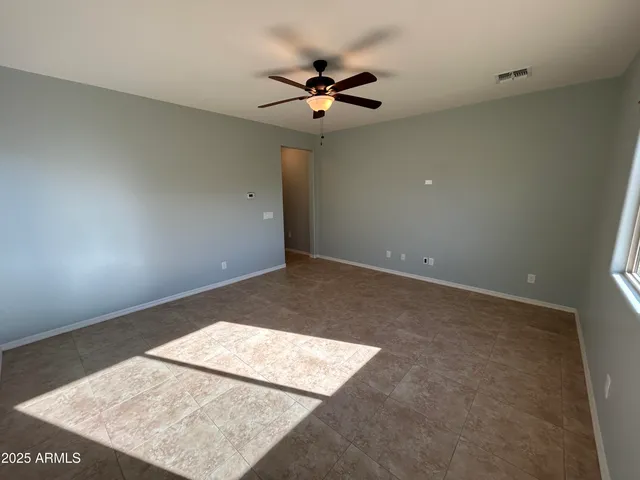 an empty room with a window and ceiling fan
