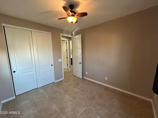 an empty room with closet and a chandelier fan