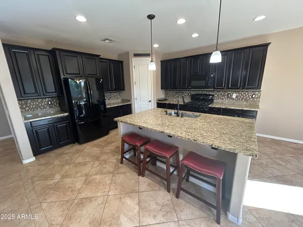 a kitchen with kitchen island a stove a refrigerator a sink and chairs