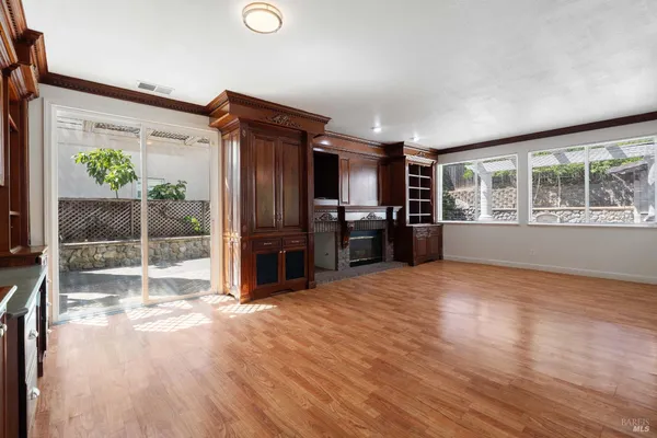 a view of empty room with kitchen and windows