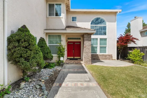 a front view of a house with a yard and potted plants