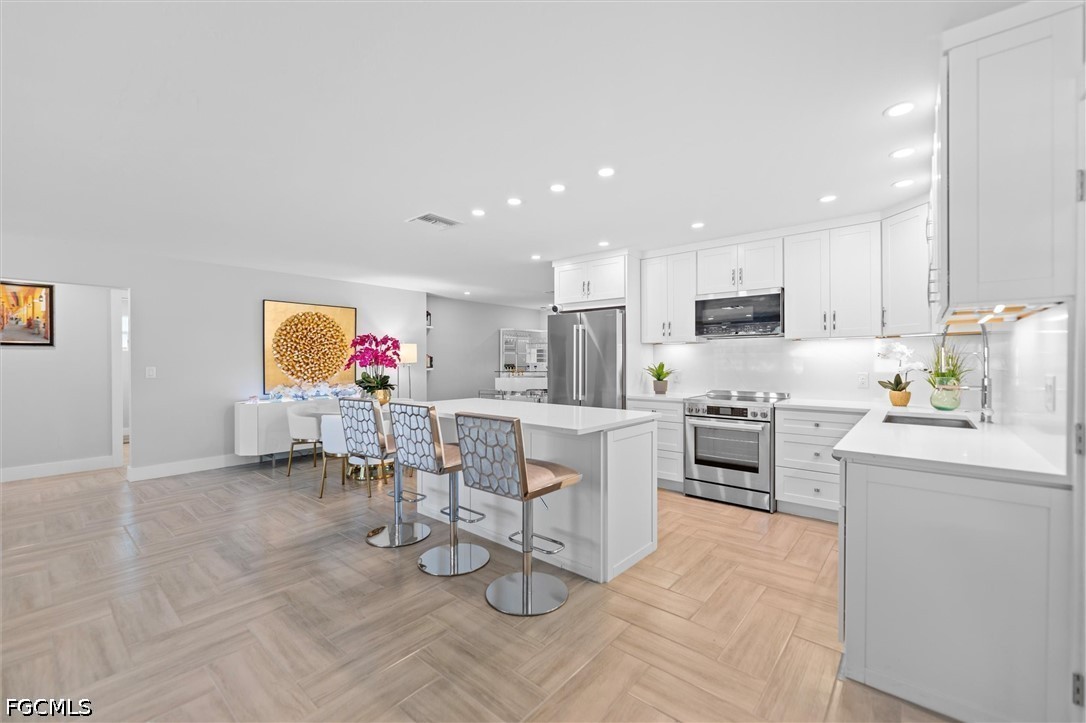 1200 Patterson Road Cape Coral, FL 33909 - Photo 6 of 42 a kitchen with white cabinets and stainless steel appliances