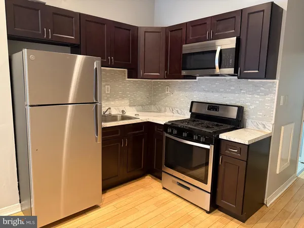 a view of a kitchen with a refrigerator and wooden floor