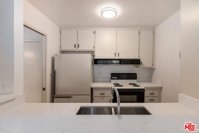 a kitchen with stainless steel appliances granite countertop a refrigerator a stove a sink and white cabinets