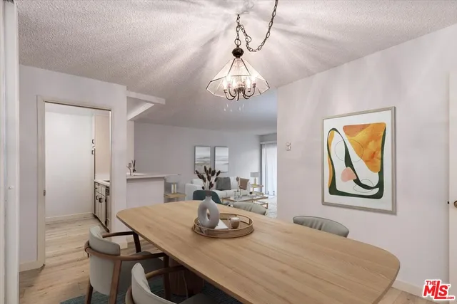 a dining room with wooden floor a chandelier a wooden table and chairs