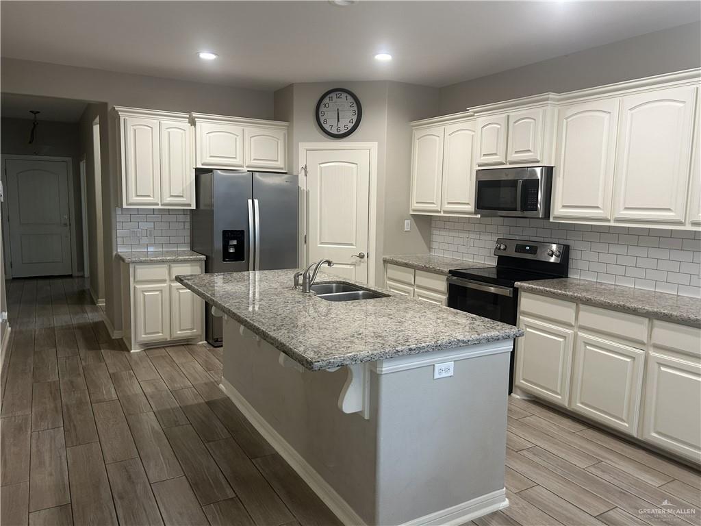 6317 Cascada Bnd Road McAllen, TX 78504 - Photo 2 of 4 a kitchen with stainless steel appliances granite countertop a sink stove microwave and refrigerator