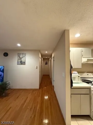 a view of a hallway with wooden floor and a living room