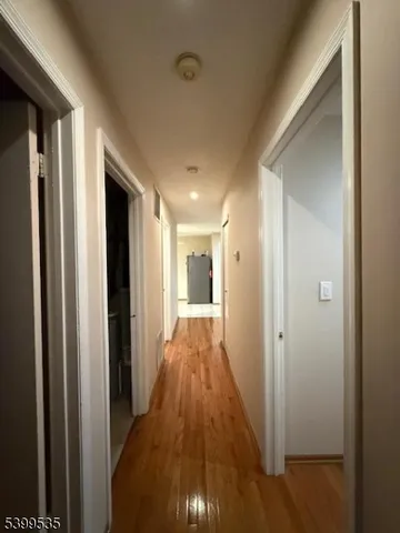 a view of a hallway with wooden floor and a bathroom