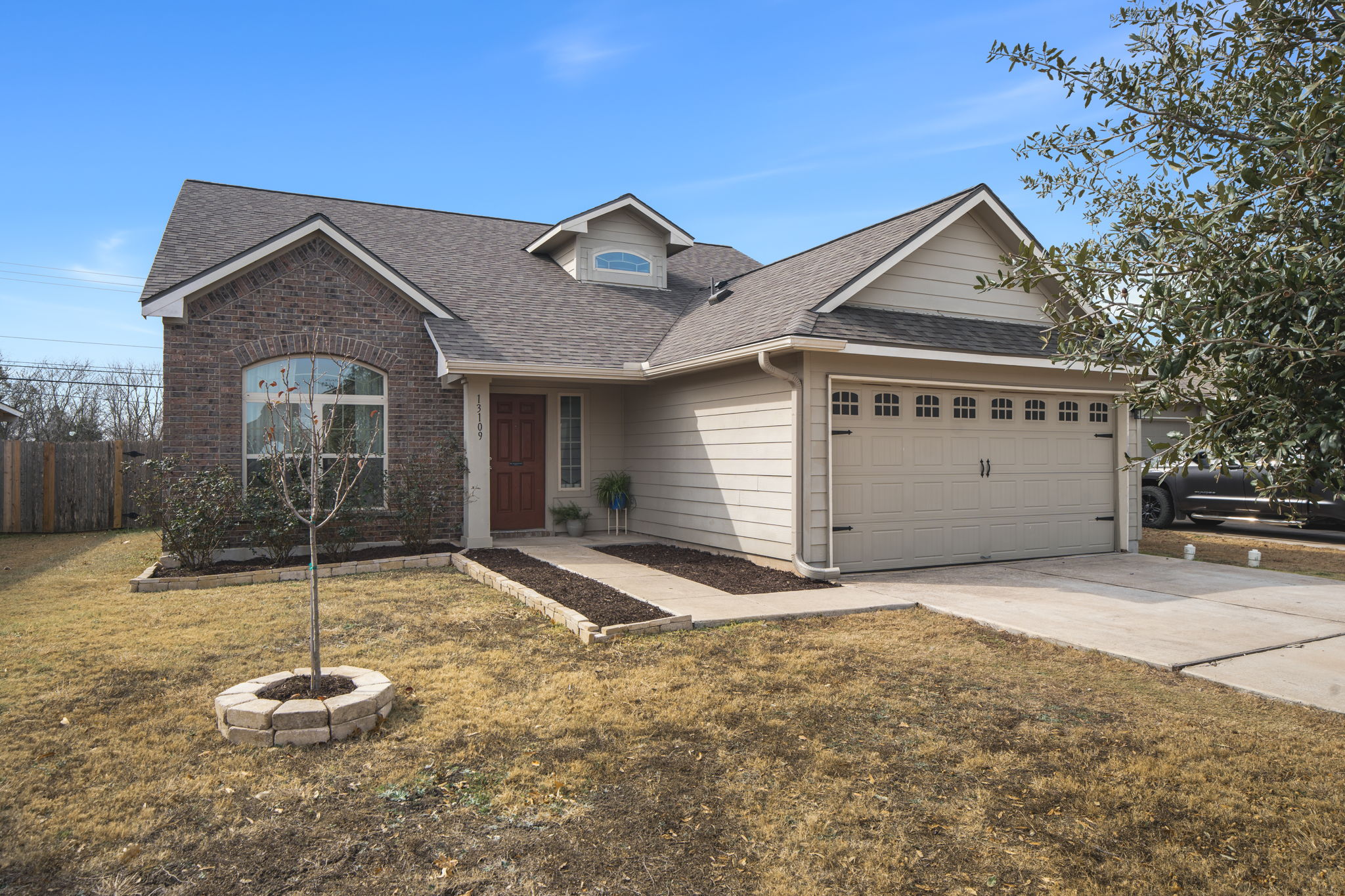 View of front facade with roof with shingles, concrete driveway, a garage, and brick siding
