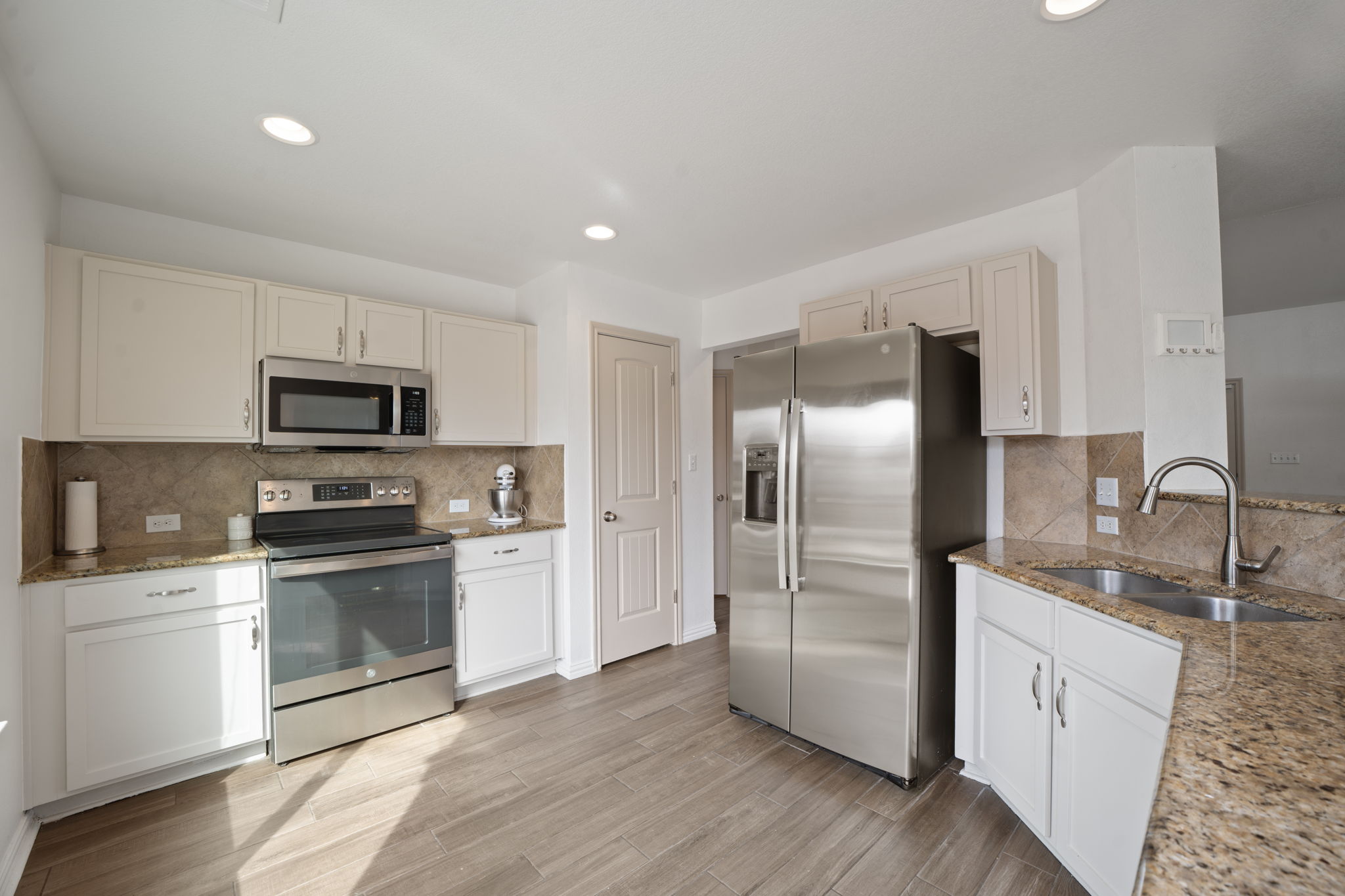 13109 Pealing Way Manor, TX 78653 - Photo 8 of 32 Kitchen featuring light stone counters, stainless steel appliances, tasteful backsplash, light wood-style floors, and recessed lighting