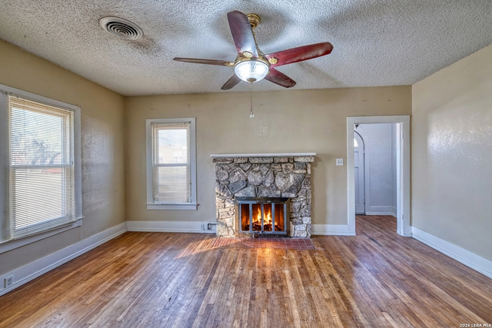 227 West Mueller Street Uvalde, TX 78801 - Photo 4 of 27 a view of an empty room with wooden floor fireplace and a window