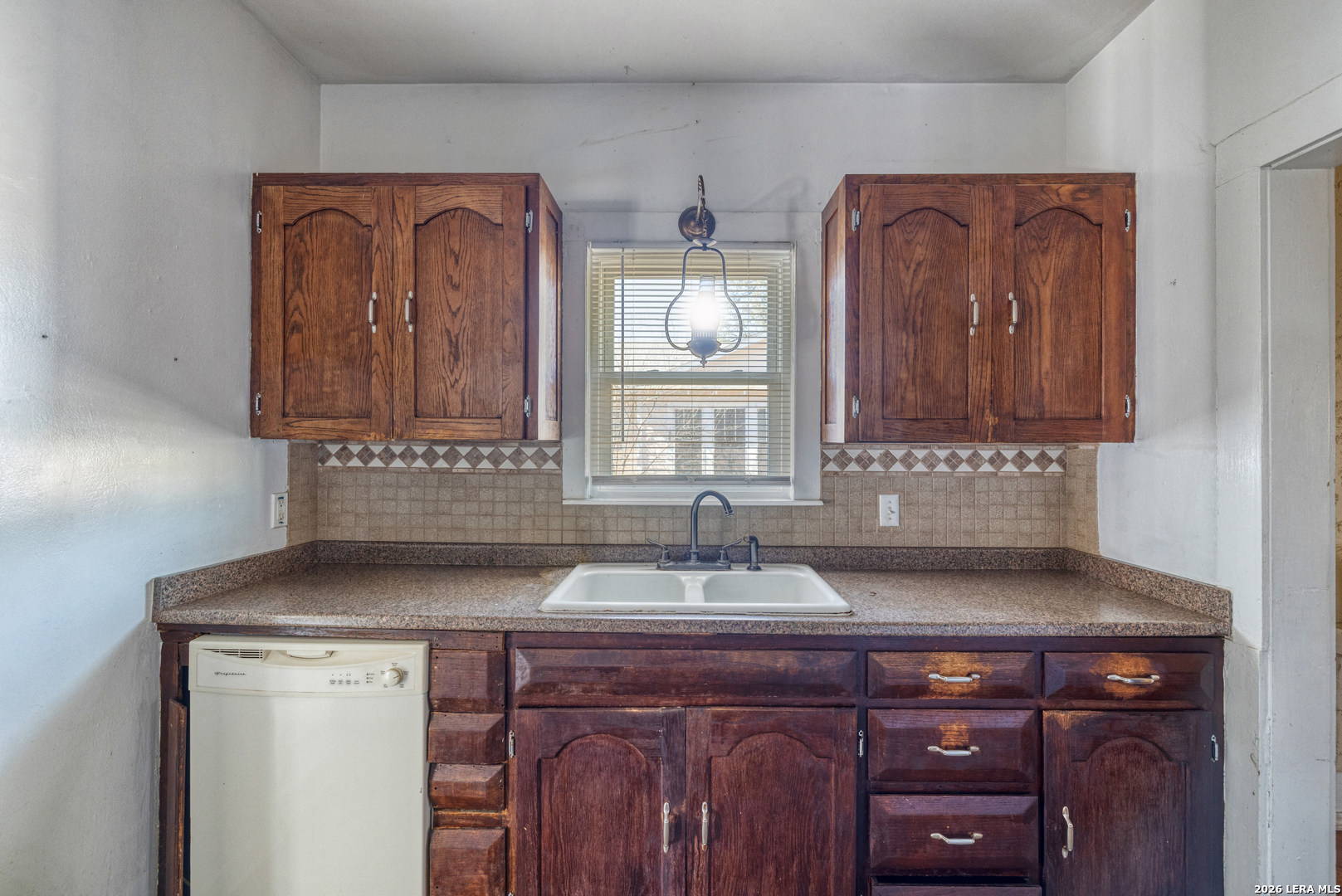 227 West Mueller Street Uvalde, TX 78801 - Photo 9 of 27 a sink with a wooden cabinets