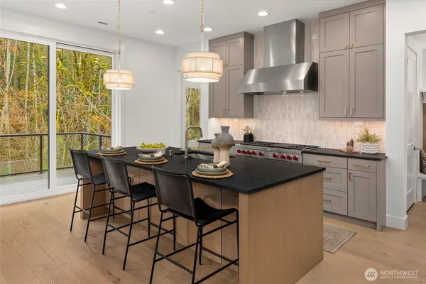 a kitchen with stainless steel appliances granite countertop a sink a stove a dining table and chairs