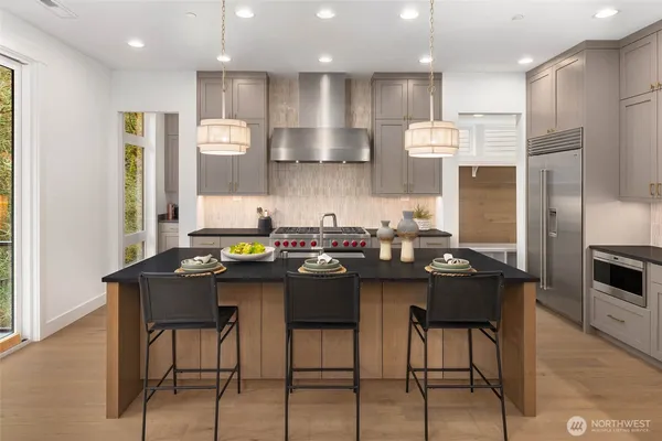 a kitchen with stainless steel appliances kitchen island granite countertop a table chairs and a sink