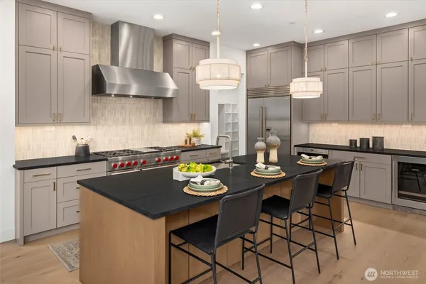 a kitchen with stainless steel appliances granite countertop a stove a refrigerator a sink a dining table and chairs with wooden floor