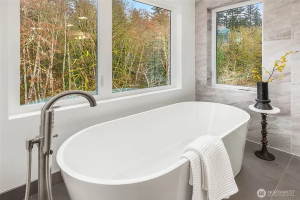a white bath tub sitting in a bathroom next to a window