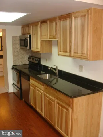 a kitchen with stainless steel appliances granite countertop a sink a stove cabinets and wooden floor