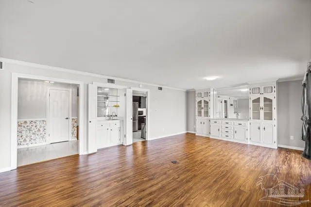 an empty room with wooden floor and a ceiling fan