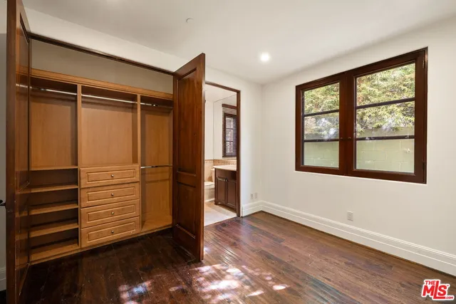 an empty room with wooden floor closet and windows