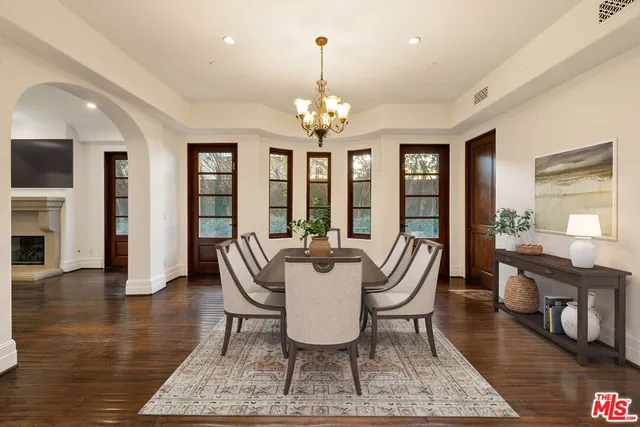 a dining room with wooden floor a chandelier a wooden table and chairs