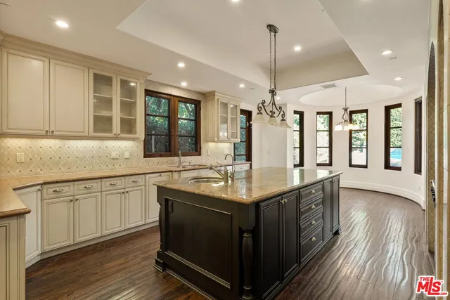 a kitchen with granite countertop a stove a sink and wooden floors