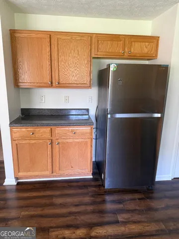 a kitchen with granite countertop a refrigerator and cabinets
