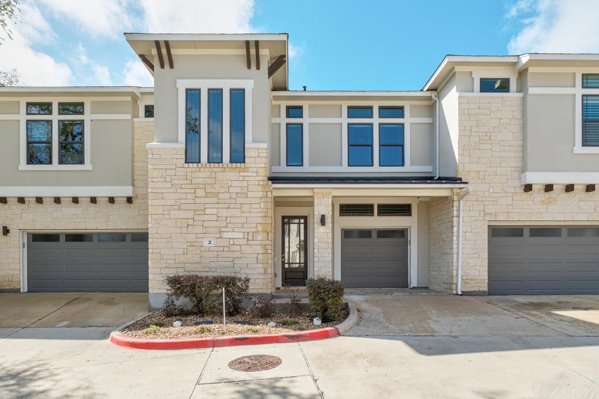 4323 Spicewood Springs Road, Unit 2 Austin, TX 78759 - Photo 2 of 30 View of front of property featuring an attached garage, stone siding, driveway, and stucco siding