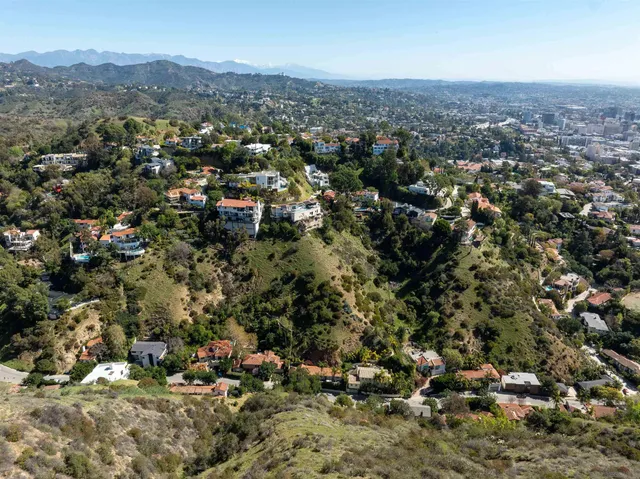 an aerial view of residential house with parking and trees
