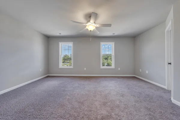 an empty room with windows and chandelier fan