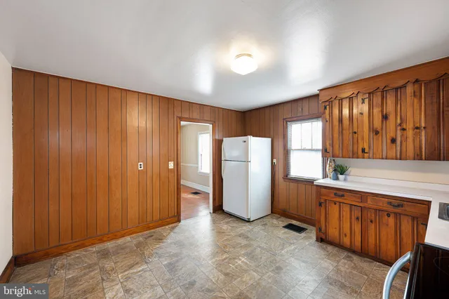 a view of a kitchen with refrigerator and wooden cabinets