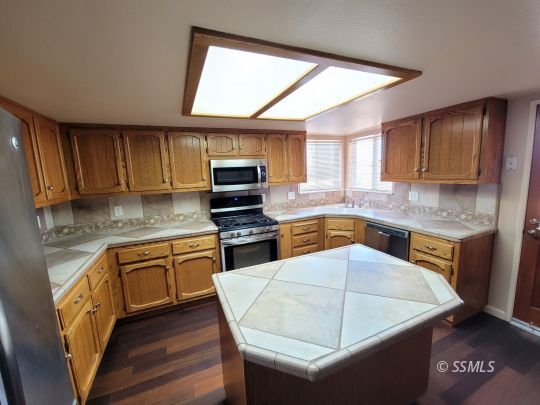 616 South Appaloosa Street Ridgecrest, CA 93555 - Photo 7 of 18 a kitchen with stainless steel appliances wooden cabinets a stove a sink and a microwave