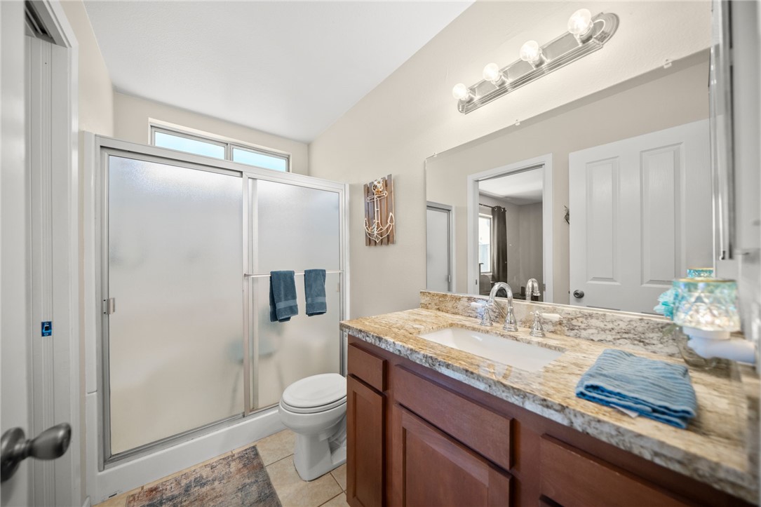 27879 Foxfire Street Menifee, CA 92586 - Photo 24 of 36 a bathroom with a granite countertop sink toilet a large mirror a shower and vanity