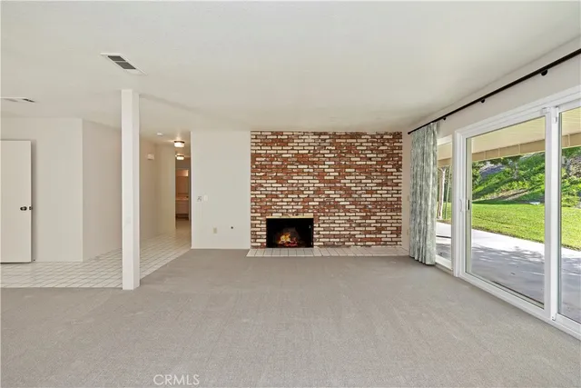 a view of an empty room with a fireplace and a large window